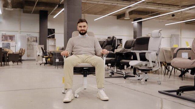 Young customer testing a new ergonomic office chair, finding comfort and satisfaction in a large furniture showroom