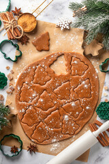 Rolled out pastry dough with cut out Christmas tree shapes on white marble table. Preparation of homemade gingerbread cookies, top view