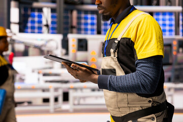 Industrial technician upgrades system data on tablet, optimizing automation in smart factory for...