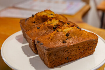 Three delectable mini banana bread loaves, studded with dark chocolate chips, presented on a white plate, offering a comforting and inviting homemade dessert or snack.
