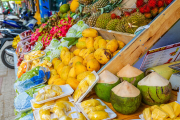 Vibrant tropical fruit stall with an abundance of fresh mangos, durians, pineapples, coconuts, and exotic produce at a bustling street market, showcasing healthy and colorful selections.