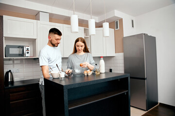 Couple prepares meal together in modern kitchen with bright lighting during morning hours
