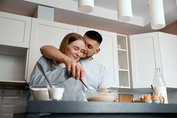 Couple cooking together in a modern kitchen while mixing ingredients for a recipe in the morning