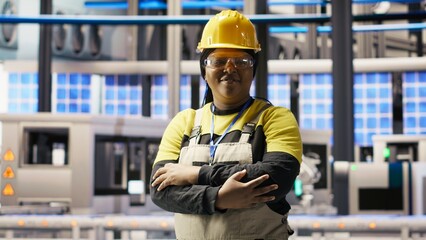 Portrait of smiling technician in industrial plant working to diagnose equipment errors. Jolly manufacturing factory professional coordinating repair tasks on assembly lines, camera B