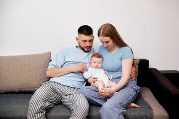Couple sitting on couch holding baby during family time in living room at home in daytime