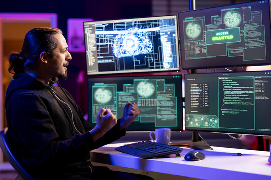 Cheerful rogue programmer delighted after getting access granted message after using undetectable malware. Hacker doing victory hand gesture after breaching firewall security using data mining script