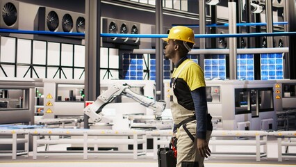 Engineer walking in smart solar manufacturing facility, using toolbox to calibrate high tech...
