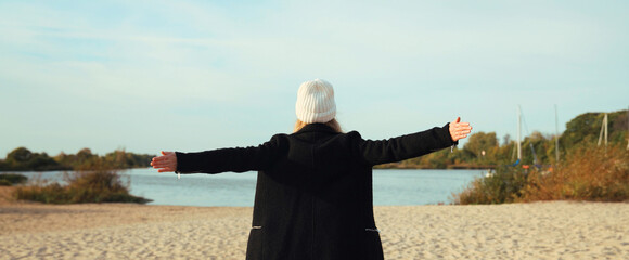 Back view of happy woman on sunny beach, joyful girl enjoying landscape, warm weather on sea coast