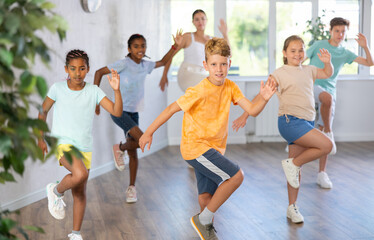 Obraz premium Positive boy exercising in group of classmates during dance class at dance studio