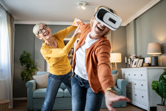 Senior women experiencing virtual reality at home, having fun - Powered by Adobe