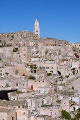 Obraz premium vertical shot of the iconic Sassi di Matera cityscape, unesco world heritage site in Basilicata, Italy, featuring the majestic cathedral bell tower.