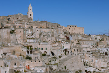 Obraz premium sassi di matera, italy: ancient, pale stone cave dwellings and historic city center under a deep blue sky. unesco world heritage site in basilicata