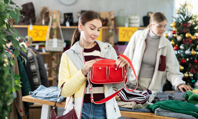 Fototapeta premium Black Friday sale, customer inspect at products in store and pick out clothes, accessories. Young woman search and choose leather handbag, purchase some wardrobe items. Style and fashion type look