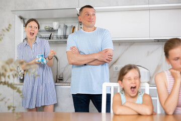Wife yells at her husband in front of children in the home kitchen