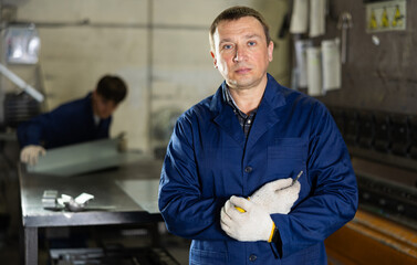 Portrait of male experienced engineer in a robe in workshop of a metallurgical plant