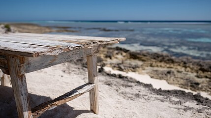 Weathered Wooden Beach Table on Sandy Shore with Ocean View and Clear Blue Sky
