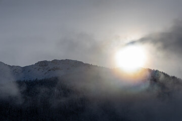 Sunlit Snowy Mountain Ridge Over Misty Forest in British Columbia, Canada