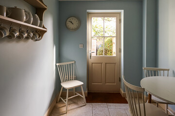 Cozy rustic dining area with light blue walls and a glass paneled door. Cotswolds countryside,...