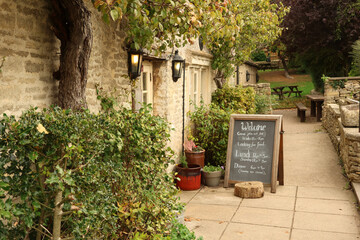 English country pub with stone facade and a welcome chalkboard menu inviting guests to a...