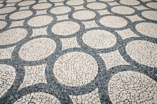 Geometric mosaic design of connected circles made from black and white paving blocks or cobbles in a traditional Portuguese calcada pavement in Porto