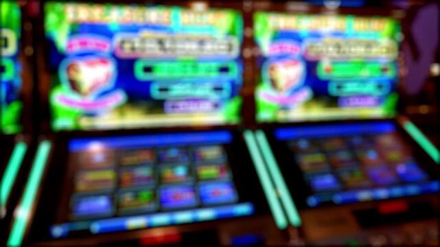 Defocused casino interior with colorful slot machines and neon lights, forming an abstract bokeh background with vibrant gaming atmosphere.