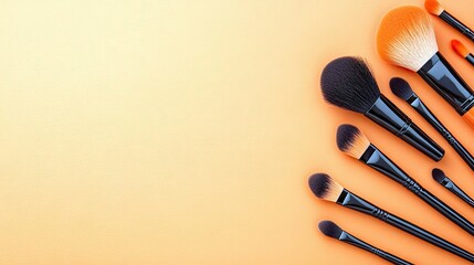 Overhead view of various makeup brushes arranged on an orange background, showcasing beauty and cosmetic tools.