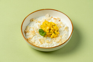 A bowl brimming with creamy coconut rice, layered with sweet mango chunks and garnished with toasted almond slices. This vibrant dish is both refreshing and satisfying, perfect for any time of day