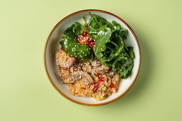 A wholesome bowl filled with fluffy quinoa, savory chicken slices, juicy red peppers, and a refreshing mix of leafy greens creates a colorful and nutritious meal