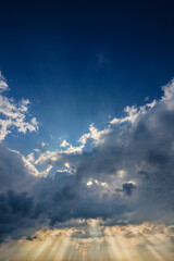 Dramatic sky with sun rays penetrating clouds