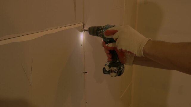 Skilled man using a power drill to secure drywall panels, showcasing craftsmanship and attention to detail in home construction process. Build house man