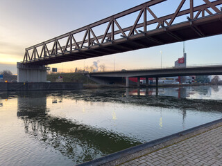 Obraz premium Truss bridge over urban canal reflecting sunset light