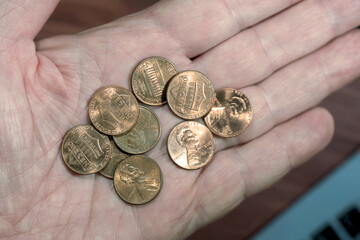 Man holding a number of US pennies in palm of hand