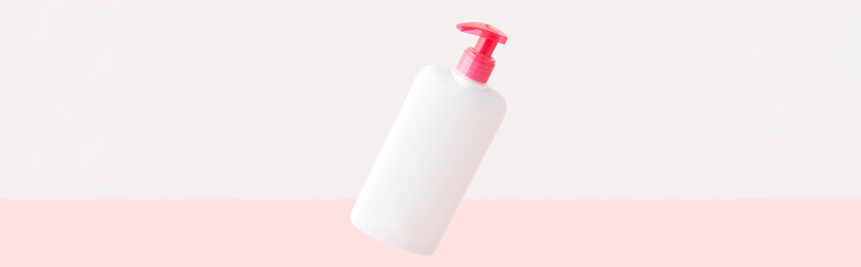 Bottle of intimate hygiene gel on pastel pink and white background. Body care concept
