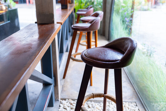 Leather bar stool with wooden legs and rope footrest near wooden counter in bright cafe interior