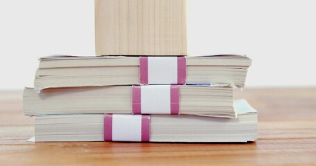 Displaying three paperback booklets stacked on wood table, showing magenta bands and wood block