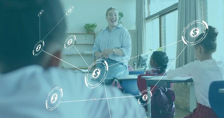 Smiling teacher wearing blue shirt and jeans, sitting on desk leading classroom with dollar overlay