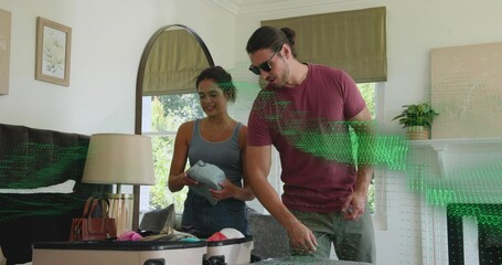 Fototapeta premium Packing couple in living room over open suitcase, woman in tank, jeans, man shades, green overlay