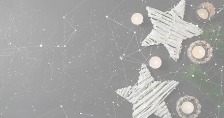 Glowing twig stars and lit tea lights creating cozy holiday scene on gray tabletop, copy space