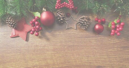 Displaying holiday garland atop wooden tabletop, showing pinecones, red baubles, star cutter
