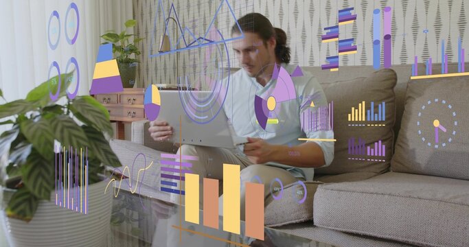 Sitting man in white shirt holding stylus and using tablet on sofa, holographic data overlays
