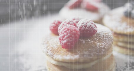 Showing stacked pancakes sitting on soft table in cafe with 3 raspberries powdered sugar doily grid