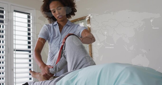 Lifting mid caregiver wearing blue shirt holding senior patient's leg in bedroom with map overlay - Powered by Adobe