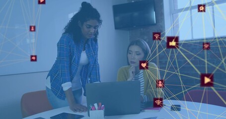 Leaning woman blue-plaid and seated peer mustard-cardigan studying laptop at meeting table, overlay