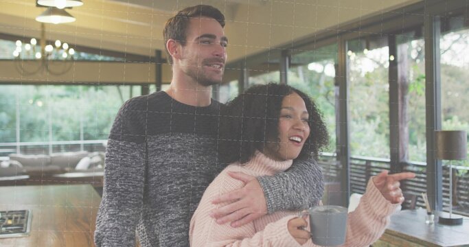 Standing couple, woman wearing pink turtleneck pointing at windows at home, holding gray mug - Powered by Adobe