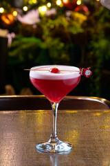 Christmas themed cherry red fruit cocktail with blurred tree in the background