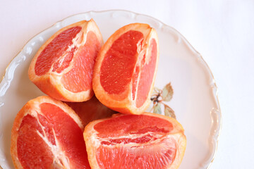 Close-up of cut grapefruit on a white vintage plate and a white background. Fruit and good nutrition. Grapefruit and sources of vitamins. Grapefruit background and natural food.