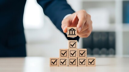 Businessman builds pyramid of wooden blocks with bank symbol on top, representing financial stability and investment success in modern office, conveying trust and growth.
