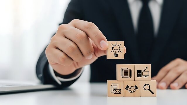 Businessman stacking wooden blocks with lightbulb symbol on office desk, representing innovative ideas and strategic planning for business growth. - Powered by Adobe