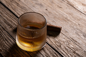 Luxury whiskey drink with cigar on vintage wooden surface. Classic whiskey and cigar still life on old wood. Whiskey glass and cigar on rustic wooden table.