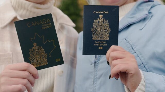 Two hands hold Canadian passports, presenting the documents clearly toward the camera.